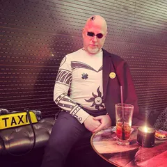 In a cyberpunk outfit at a bar, painted sleeves and a visor.