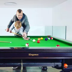 Teaching my son to line up a shot at a pool table.