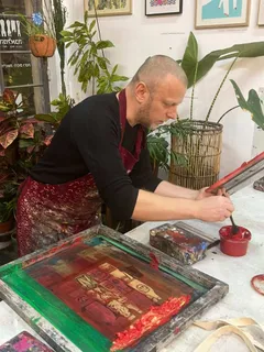 Pulling a screen print in a studio, mixing red ink beside the frame.