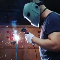 Welding a steel bar in a mask, sparks coming off the joint.